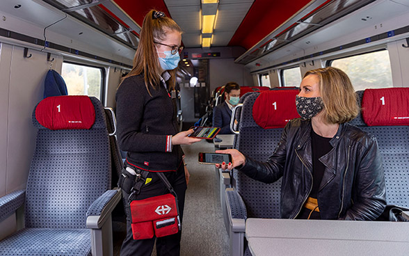 Des voyageurs et une contrôleuse portant un masque dans le train.